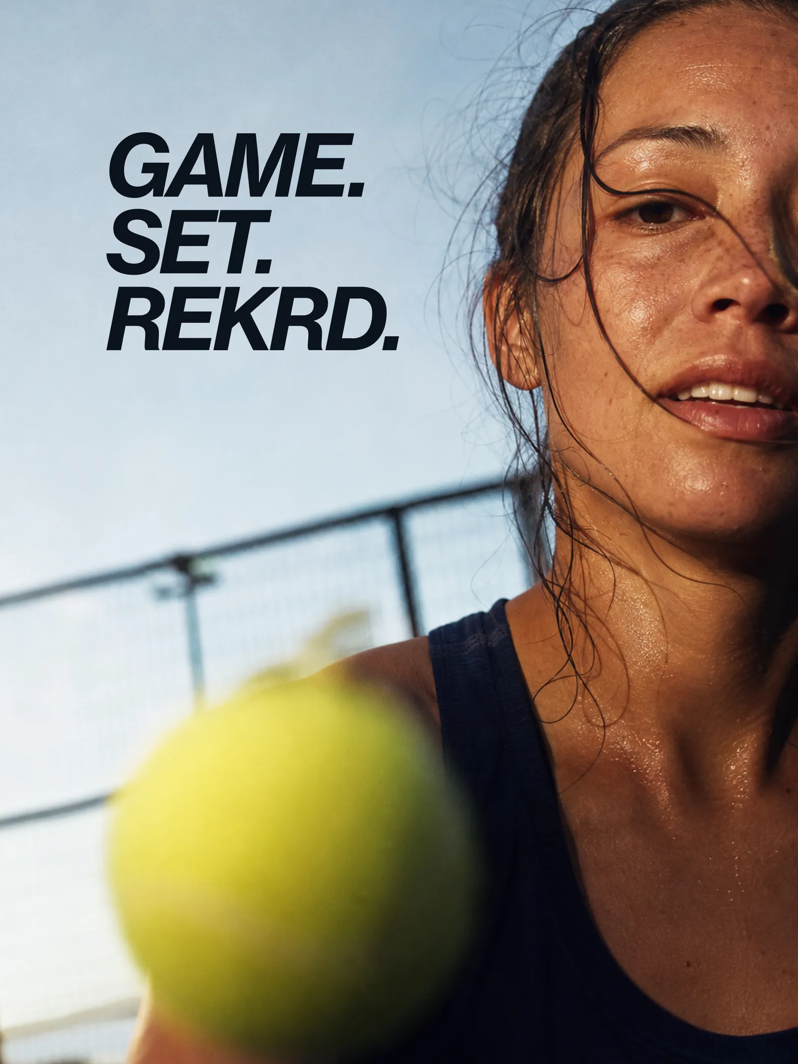 A tennis player mid-match in hard sunlight, sweat on her face, with the line Game. Set. REKRD.